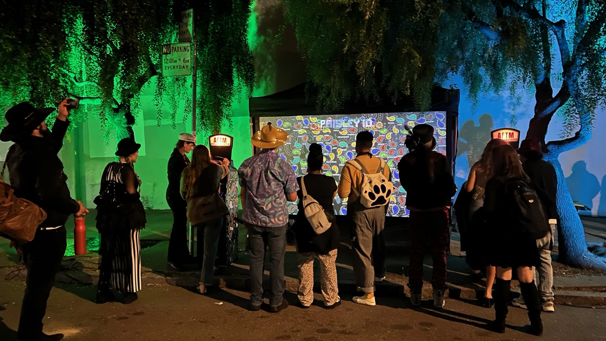A crowd at night in front of a large aquarium screen, an AFTM on each side
