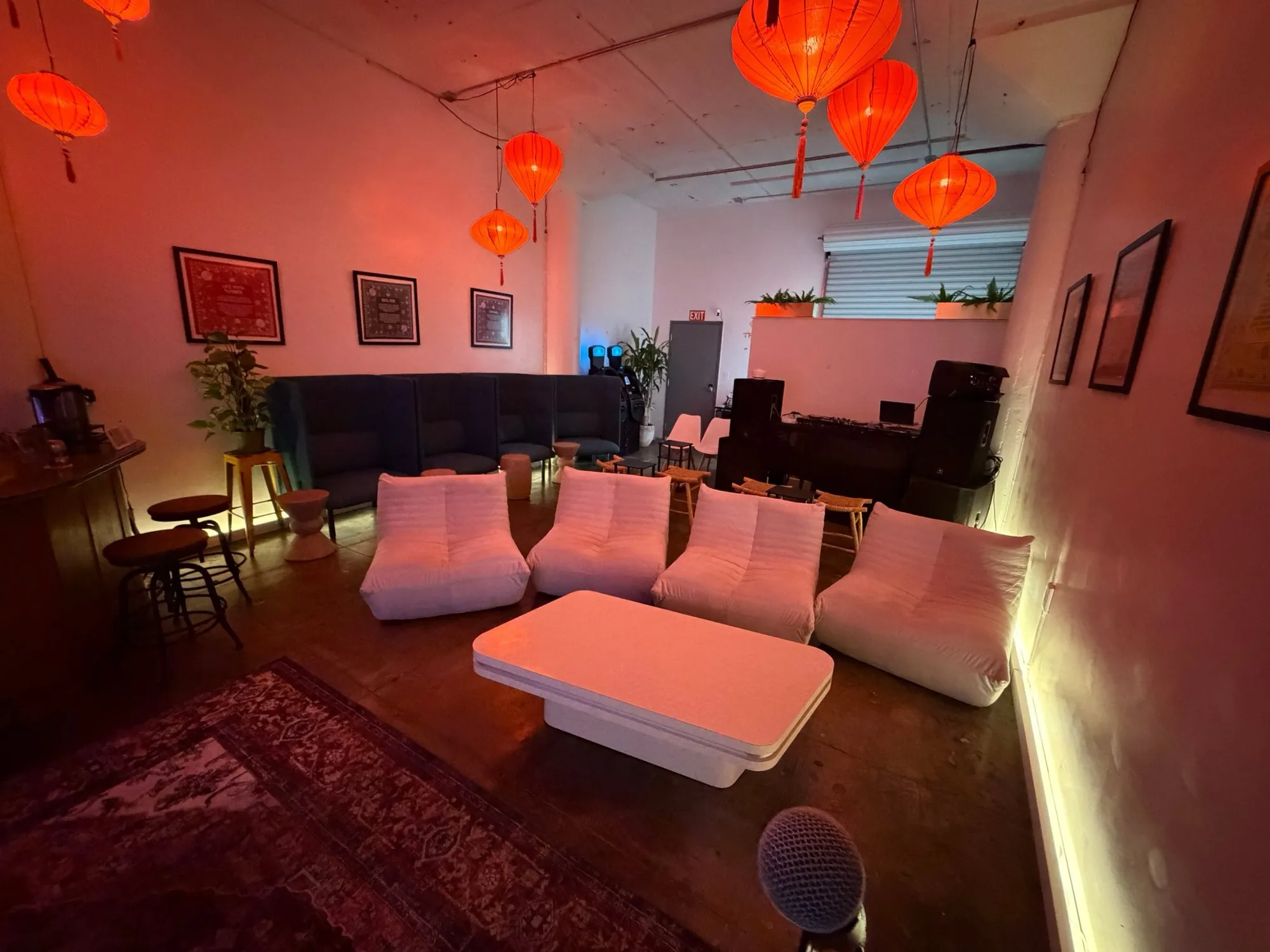 The Den set up before guests arrive: white lounge seats, a low table and red lanterns